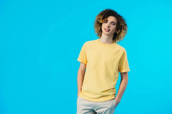 Adolescente encaracolado com as mãos em bolsos isolados em azul — Fotografia de Stock