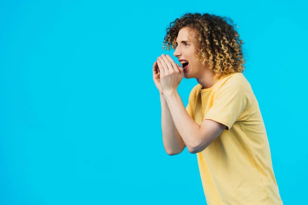 Angry curly teenager yelling isolated on blue — Stock Photo