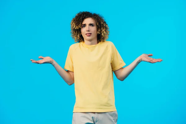 Adolescent bouclé confus montrant geste haussant les épaules isolé sur bleu — Photo de stock