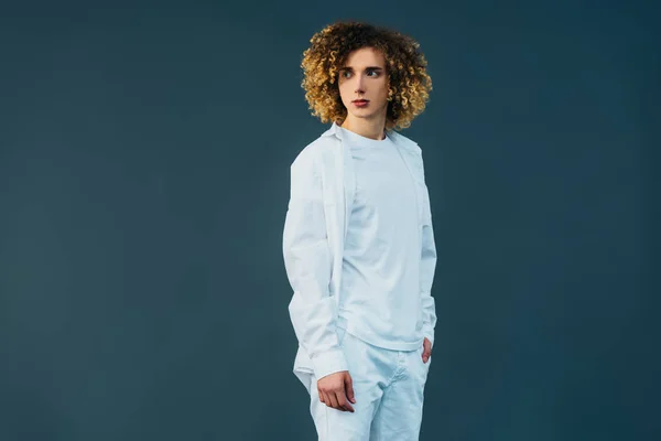 Lockiger Teenager im ganz weißen Outfit, der isoliert auf Grün wegschaut — Stockfoto