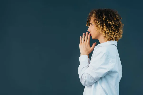 Side view of curly teenager in total white outfit with praying hands isolated on green — Stock Photo