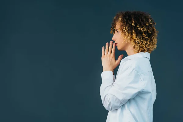 Vue latérale de l'adolescent bouclé en tenue blanche totale avec les mains priantes isolées sur vert — Photo de stock