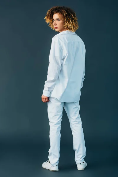 Vista posteriore di adolescente riccio in total white outfit isolato sul verde — Foto stock