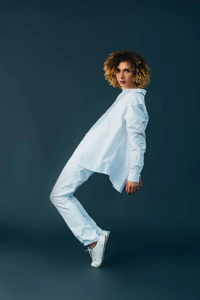 Vista lateral de adolescente encaracolado em roupa branca total posando na ponta dos pés isolado no verde — Fotografia de Stock