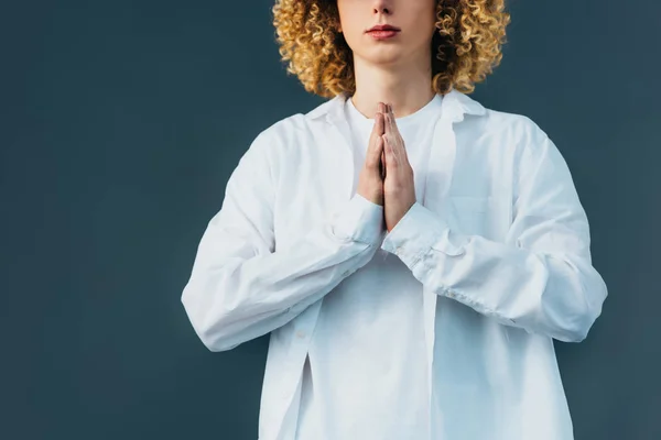 Cropped view of curly teenager in total white outfit with praying hands isolated on green — Stock Photo