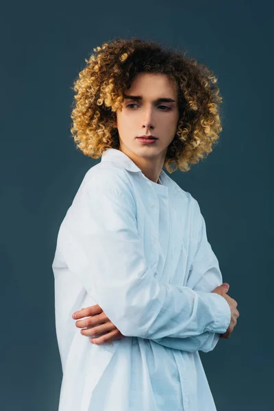 Sad curly teenager in total white outfit with crossed arms isolated on green — Stock Photo