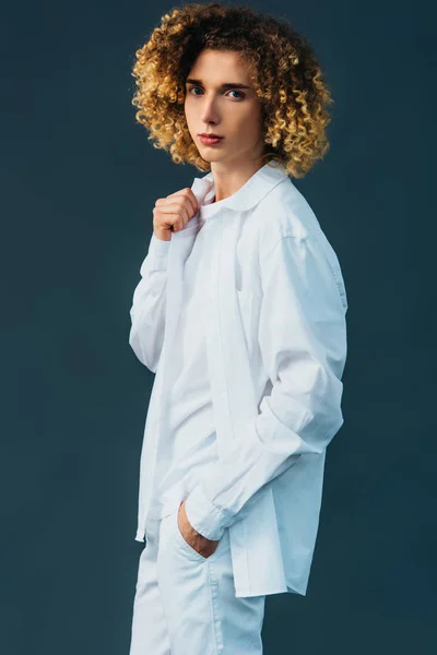 Adolescent bouclé en tenue blanche totale avec la main dans la poche isolé sur vert — Photo de stock