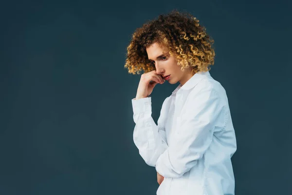 Thoughtful curly teenager in total white outfit isolated on green — Stock Photo