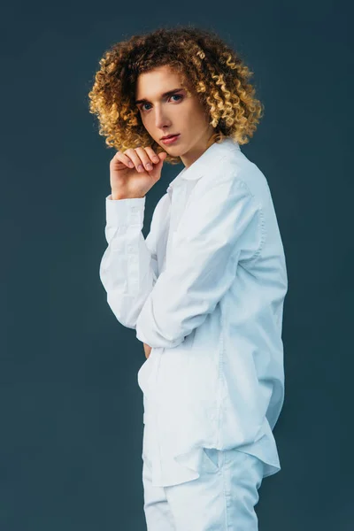 Curly teenager in total white outfit looking at camera isolated on green — Stock Photo