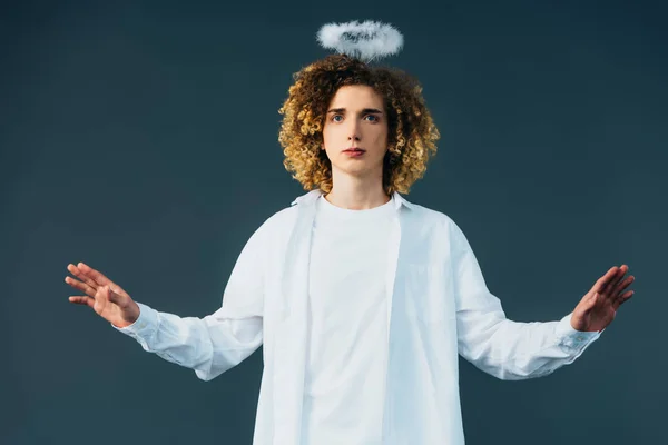 Curly teenager in angel costume with halo above head and outstretched hands isolated on green — Stock Photo