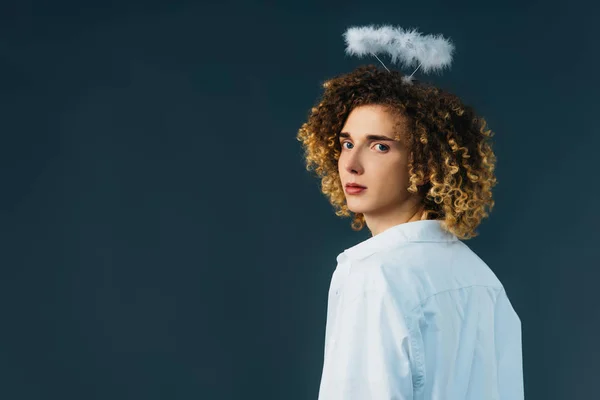 Back view of curly teenager in angel costume with halo above head isolated on green — Stock Photo