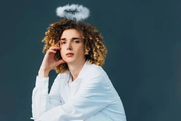 Dreamy curly teenager in angel costume with halo above head isolated on green — Stock Photo