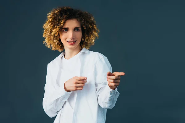 Smiling stylish curly teenager in total white outfit pointing with fingers away isolated on green — Stock Photo