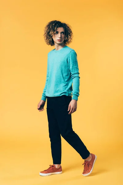 Curly teenager walking on yellow background — Stock Photo