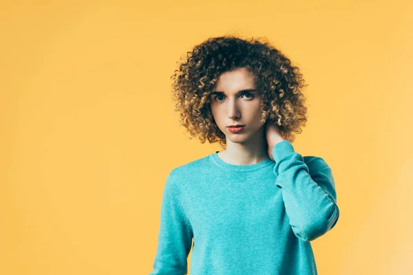 Curly teenager touching neck isolated on yellow — Stock Photo