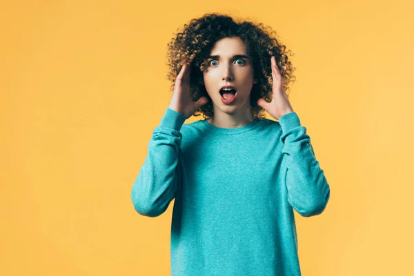 Scared curly teenager with open mouth isolated on yellow — Stock Photo