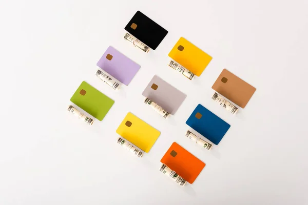 Top view of colorful credit card templates near cash rolls isolated on white — Stock Photo