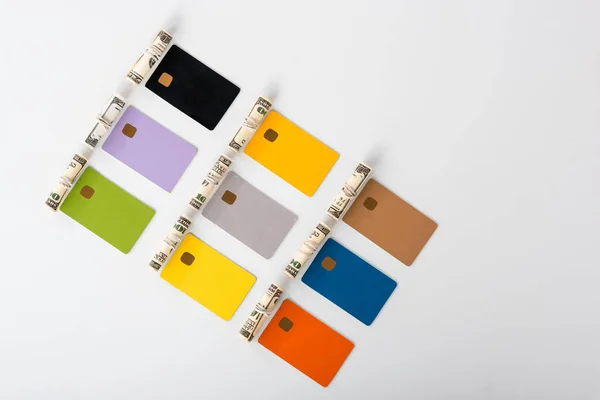 Top view of multicolored credit card templates near cash rolls on white — Stock Photo