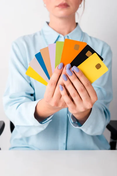 Обрізаний вид жінки, що тримає барвисті шаблони кредитних карток ізольовані на білому — стокове фото
