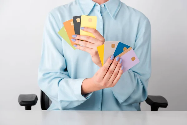 Vista recortada de la mujer sosteniendo plantillas de tarjetas de crédito multicolores en manos aisladas en blanco - foto de stock