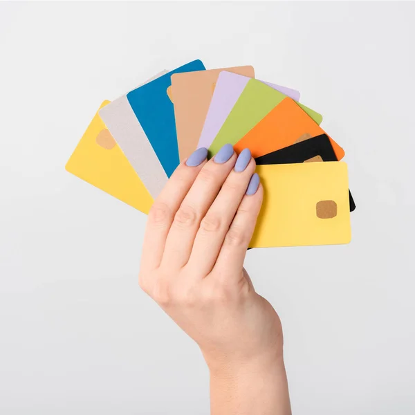 Vista recortada de la mujer con plantillas de tarjetas de crédito de colores en la mano aislado en blanco - foto de stock