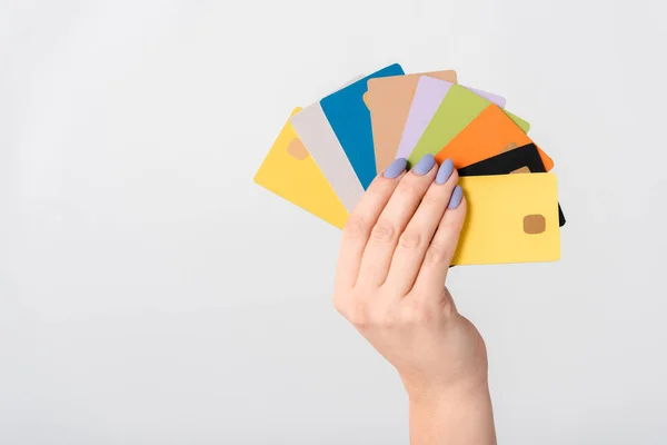 Vista recortada de la mujer sosteniendo plantillas de tarjetas de crédito multicolores en la mano aisladas en blanco - foto de stock