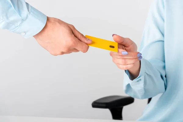 Vista recortada del hombre dando plantilla de tarjeta de crédito amarillo a la mujer aislado en blanco - foto de stock