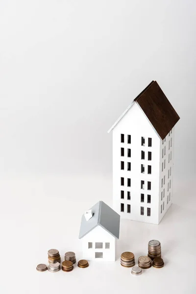 Carton houses near stacks with coins on white — Stock Photo