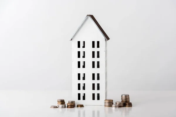 Carton house near stacks with golden and silver coins on white — Stock Photo