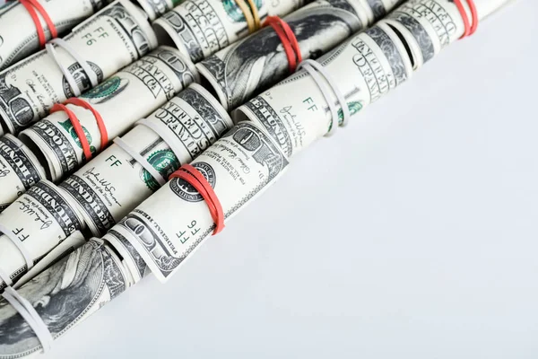 Banconote in dollari in rotoli di contante con elastici colorati su bianco — Foto stock