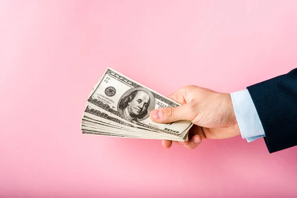 Vista cortada de homem segurando notas de dólar na mão isolado em rosa — Fotografia de Stock