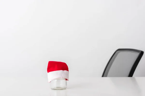 Piccolo cappello di Babbo Natale su vaso di vetro vuoto su bianco — Foto stock
