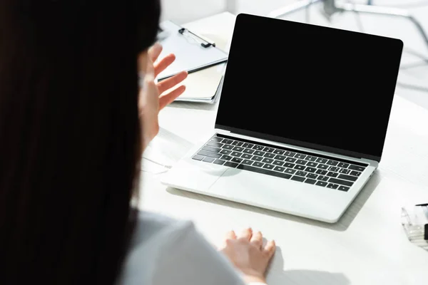 Vue recadrée du médecin ayant la consultation en ligne avec le patient sur ordinateur portable dans la clinique — Photo de stock