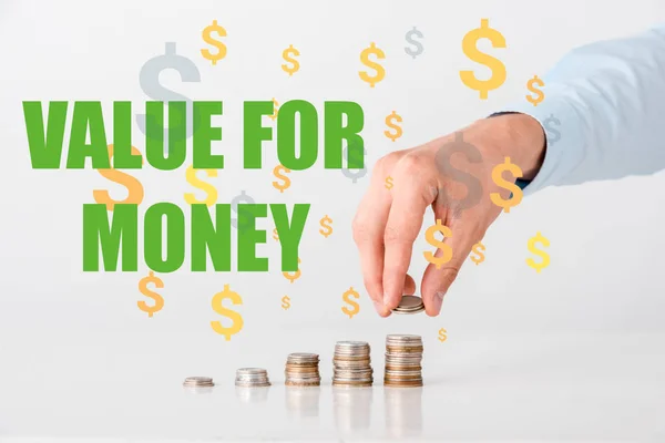 Cropped view of man touching stack of coins near value of money letters and orange dollar signs on white — Stock Photo