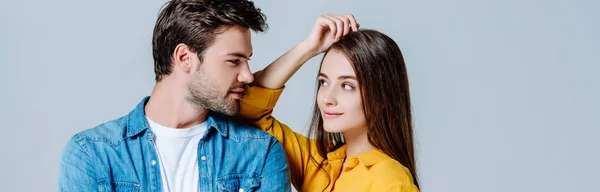 Joven pareja en denim mirando el uno al otro aislado en gris, tiro panorámico - foto de stock