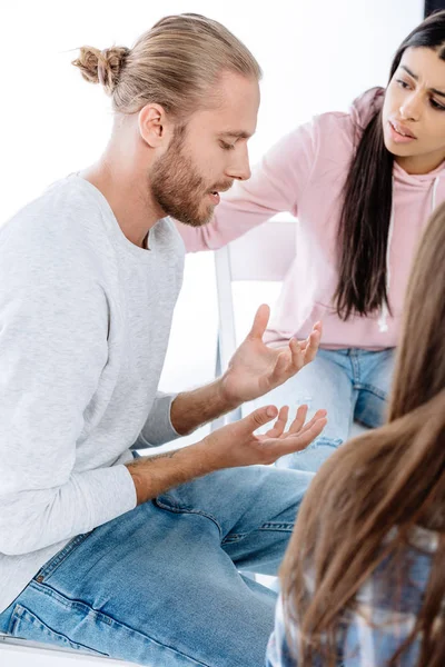 Grupo de apoyo ayudando a triste hombre en silla aislado en blanco - foto de stock