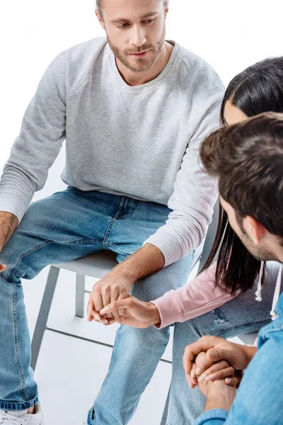 Zwei Männer halten Händchen mit afrikanisch-amerikanischem Mädchen auf Stuhl während der Selbsthilfegruppe isoliert auf weiß — Stockfoto