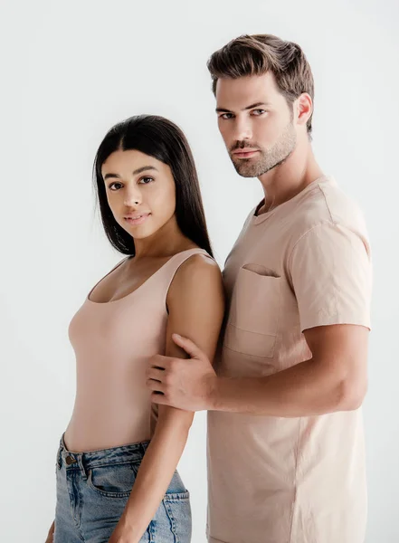 Joven interracial pareja en beige traje posando juntos aislado en blanco - foto de stock