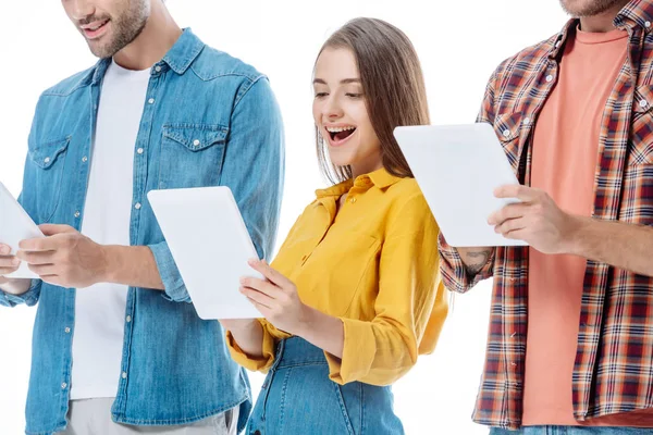 Excitada chica usando tableta digital cerca de amigos aislados en blanco - foto de stock