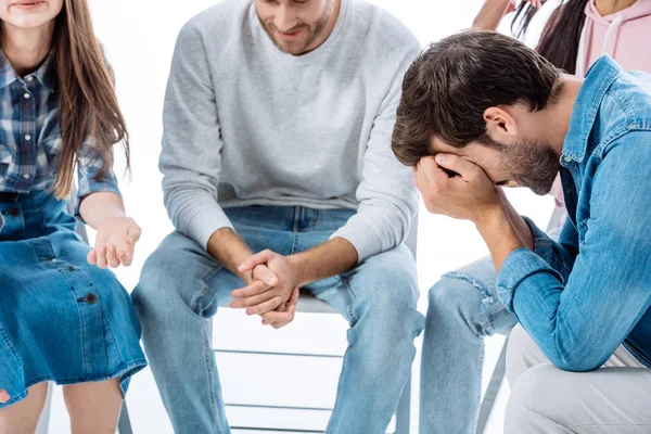 Triste homme assis sur la chaise près du groupe de soutien isolé sur blanc — Photo de stock