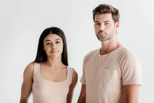 Joven interracial pareja en beige traje posando juntos aislado en blanco - foto de stock