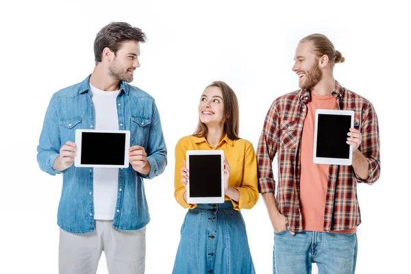 Smiling three young friends holding digital tablets with blank screens isolated on white — Stock Photo