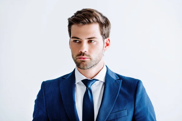 Guapo hombre de negocios en traje azul mirando hacia otro lado aislado en blanco - foto de stock