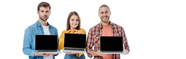 Happy young friends holding laptops with blank screens isolated on white, panoramic shot — Stock Photo