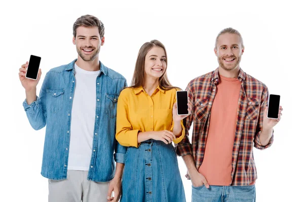 Lächelnd halten drei junge Freunde Smartphones mit weißen Bildschirmen in der Hand — Stockfoto
