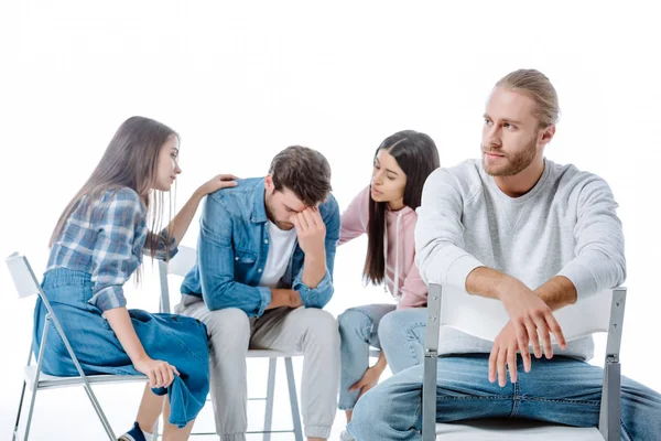 Man sitting on chair near multicultural support group helping another man isolated on white — Stock Photo