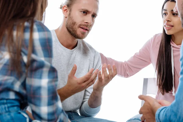 Multicultural support group helping sad man on chair isolated on white — Stock Photo