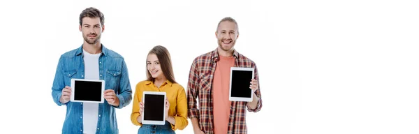 Lächelnd halten drei junge Freunde digitale Tablets mit leeren Bildschirmen, isoliert auf weißen, panoramischen Aufnahmen — Stockfoto