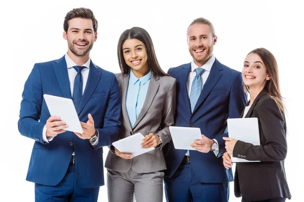 Sonrientes personas de negocios multiculturales en trajes que sostienen tabletas digitales aisladas en blanco - foto de stock