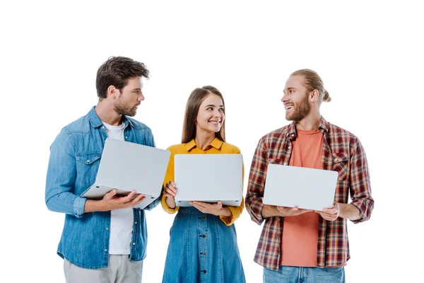 Sonriendo tres jóvenes amigos sosteniendo ordenadores portátiles aislados en blanco - foto de stock